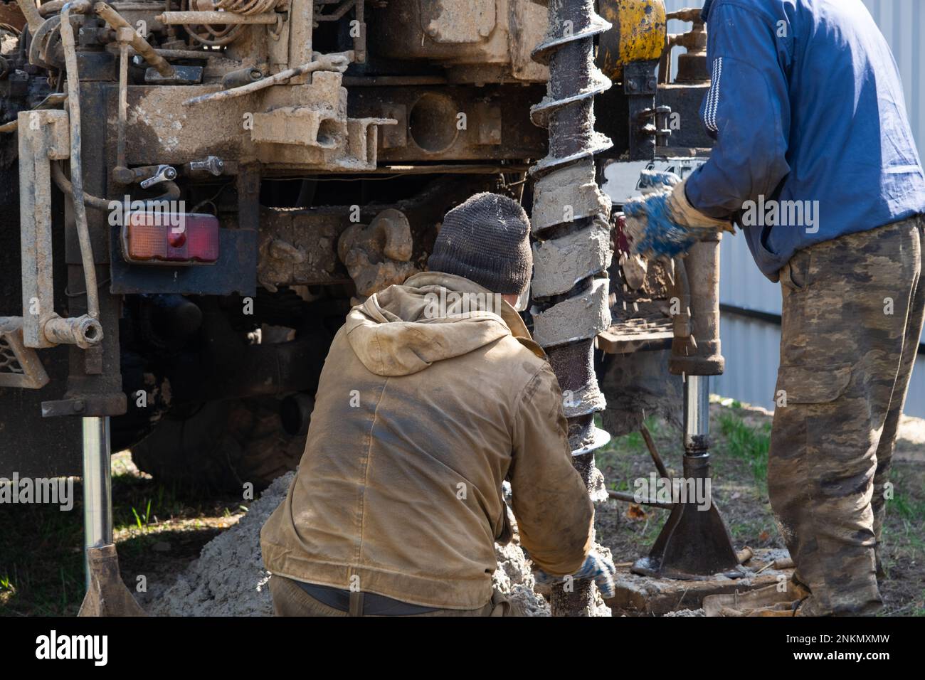 Team of workers with drilling rig on car are drilling artesian well for