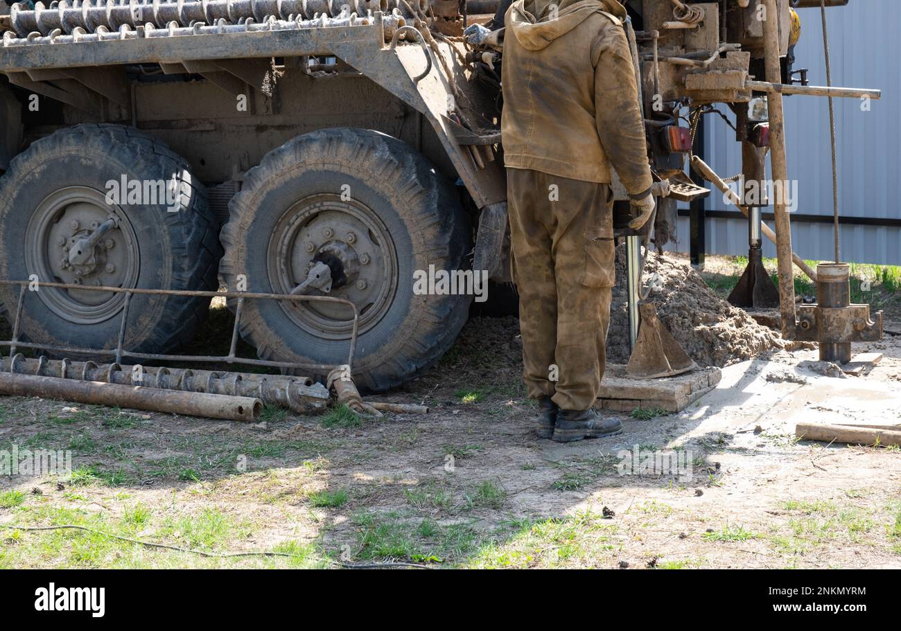 Team of workers with drilling rig on car are drilling artesian well for