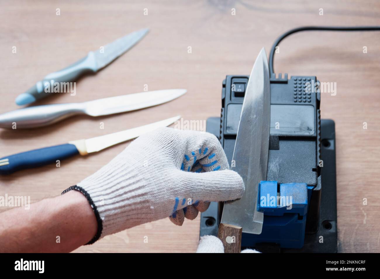 Sharpening a knife on an electric sharpener at home. The man's hand