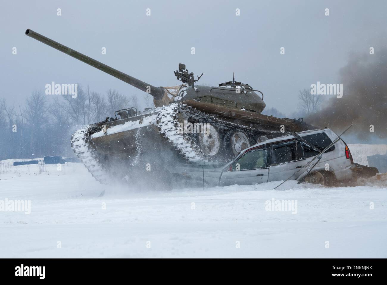 KRASNOYE SELO, RUSSIA - FEBRUARY 19, 2023: A Soviet tank T-54 crushes a old passenger car in a snowy field. Tank show in the military historical park Stock Photo