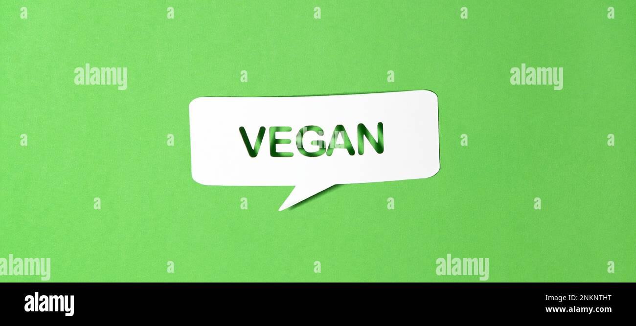 English text vegan in paper speech bubble punched out on green paper