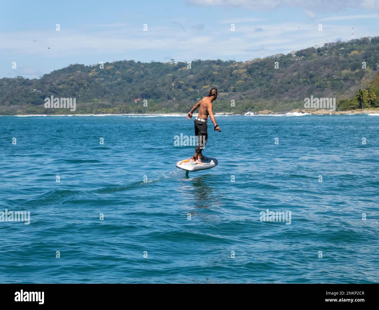 A man rides an E-Foil across the surface of the water near the coastline of Malpais Stock Photo