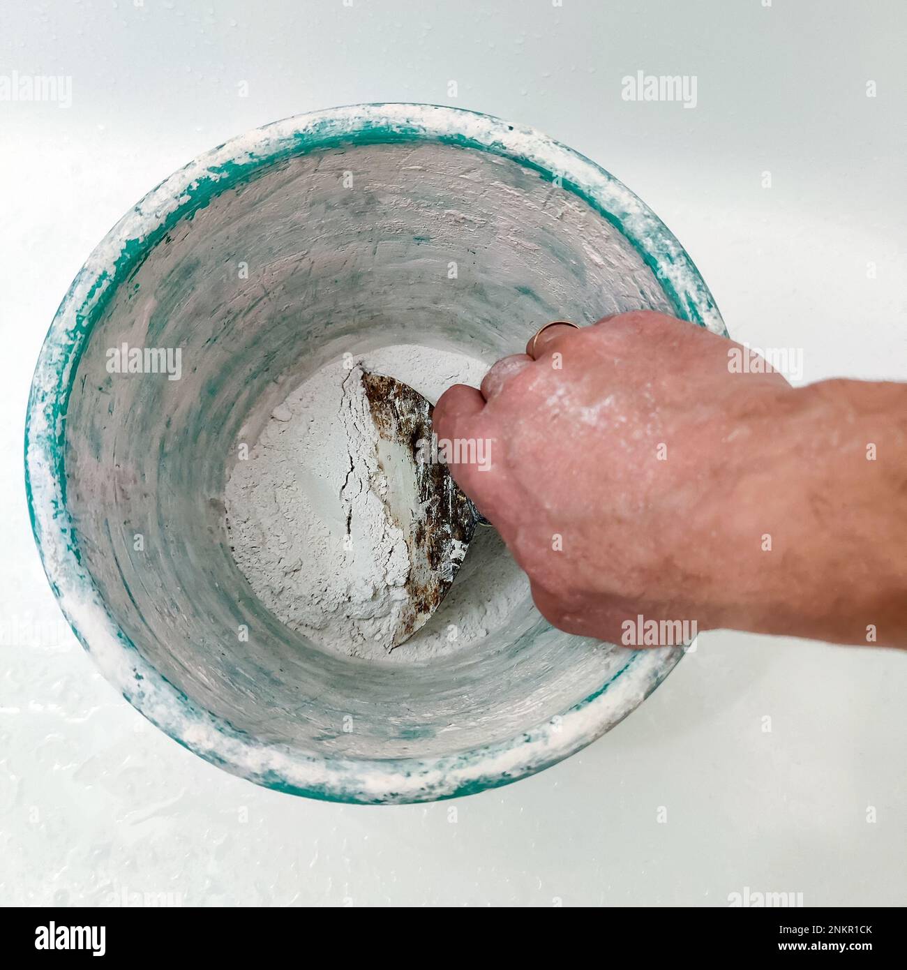 Man holds spatula against the background of old plastic bucket. Process