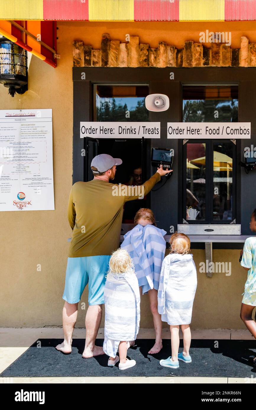 Father with three children ordering refreshments at serving hatch Stock Photo