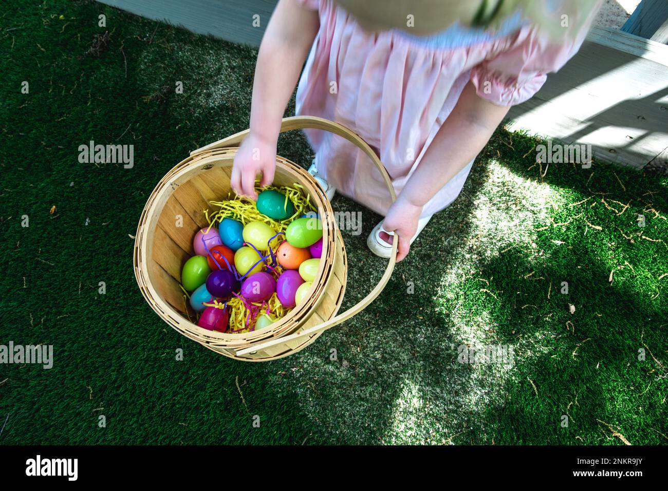 Overhead of girl carrying basket with colorful painted Easter eggs Stock Photo