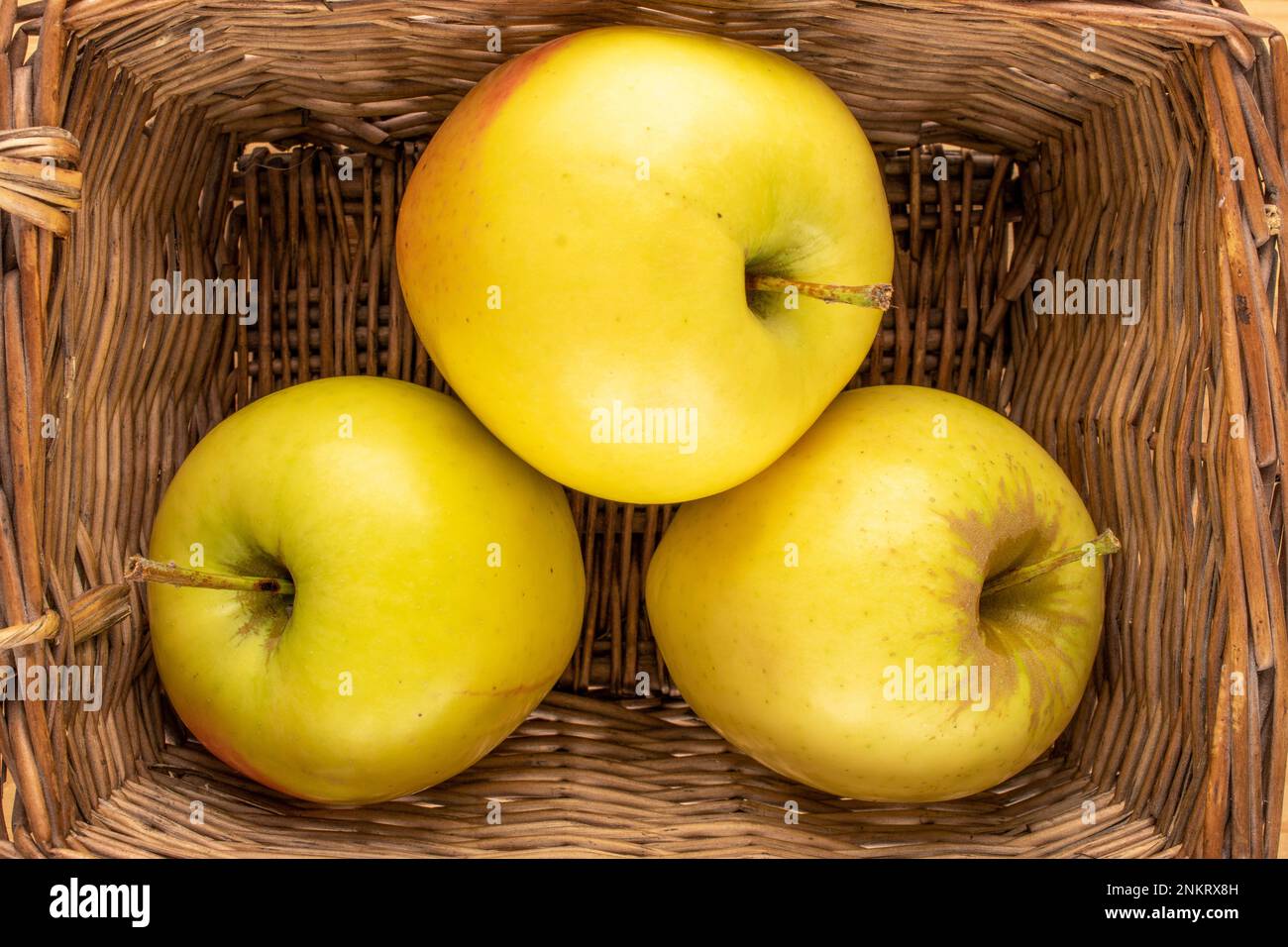 Three yellow organic apples in a basket, macro, top view. Stock Photo