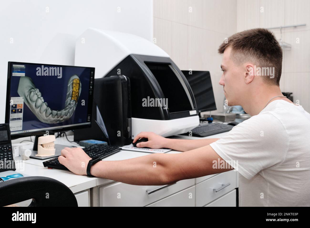 Dental technician working with a computer in a laboratory. 3D modeling of the crown in the dental lab Stock Photo