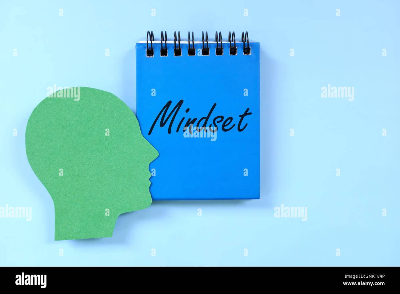 Proper mindset in personal development concept. Human head profile beside blue notepad with written text. Stock Photo