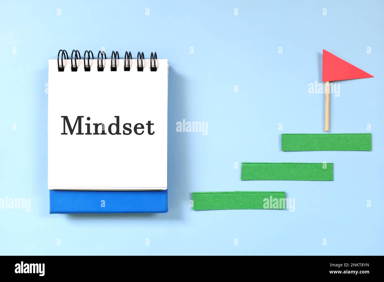Proper mindset in career and business success concept. Ladder of success beside blue notepad with written text. Stock Photo