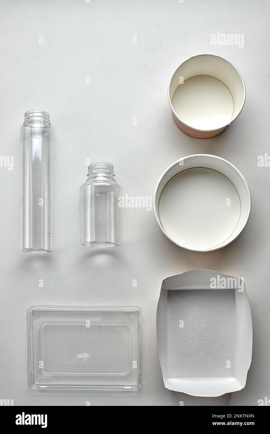 Various disposable tableware bottles and containers on a white background. Vertical Stock Photo
