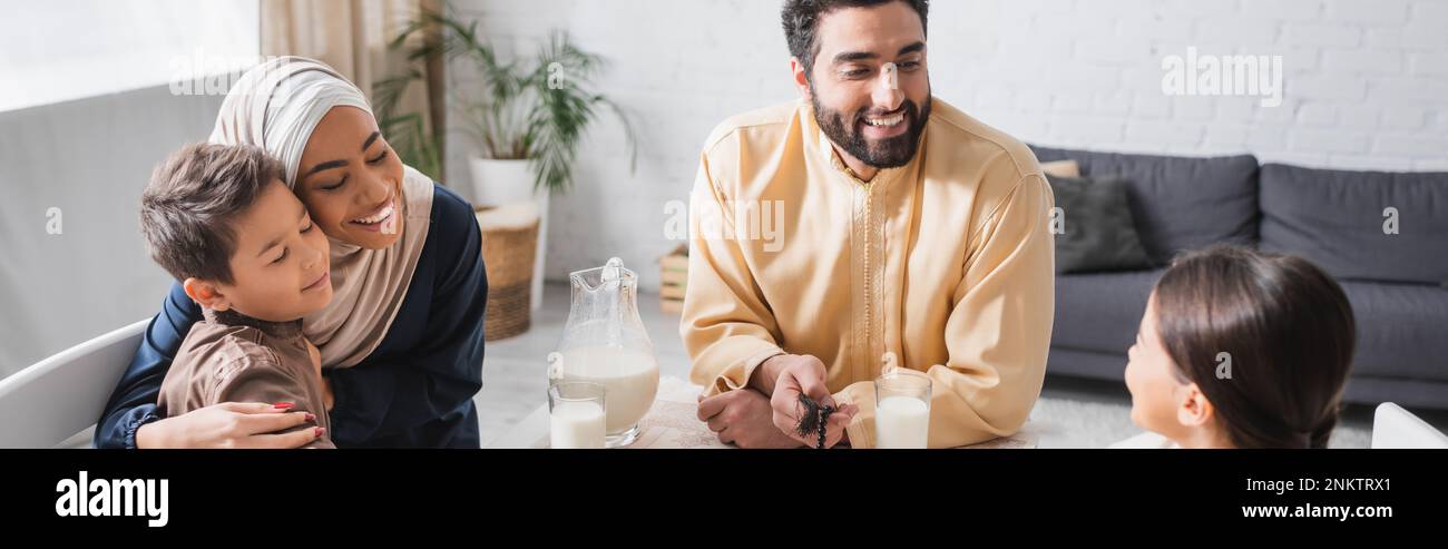 Positive middle eastern family talking during suhur in morning at home, banner,stock image Stock Photo