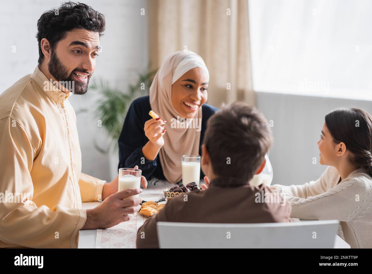 Muslim father talking to son near happy family during suhur breakfast,stock image Stock Photo