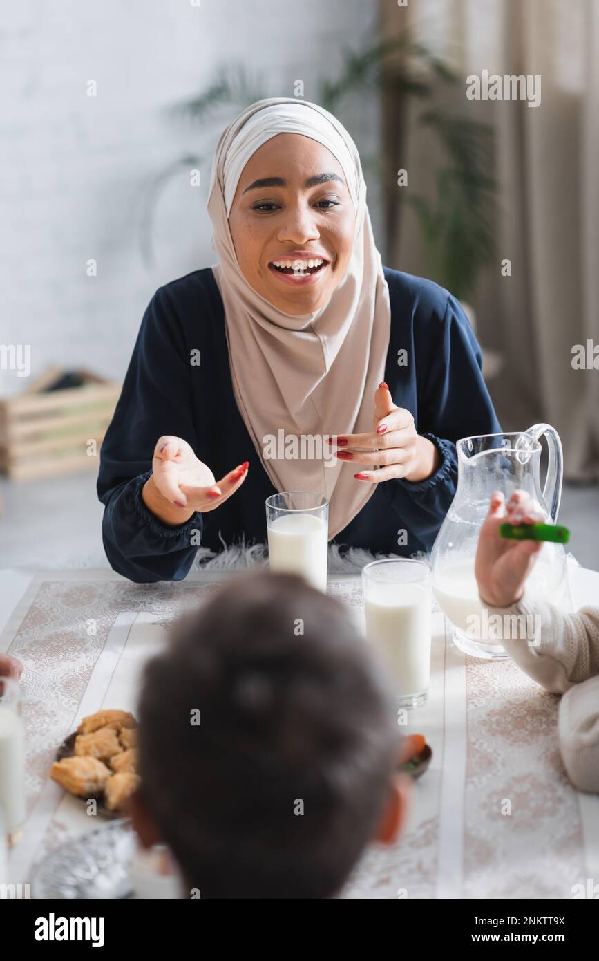 Smiling african american mother in hijab talking to kids during suhur breakfast at home,stock image Stock Photo