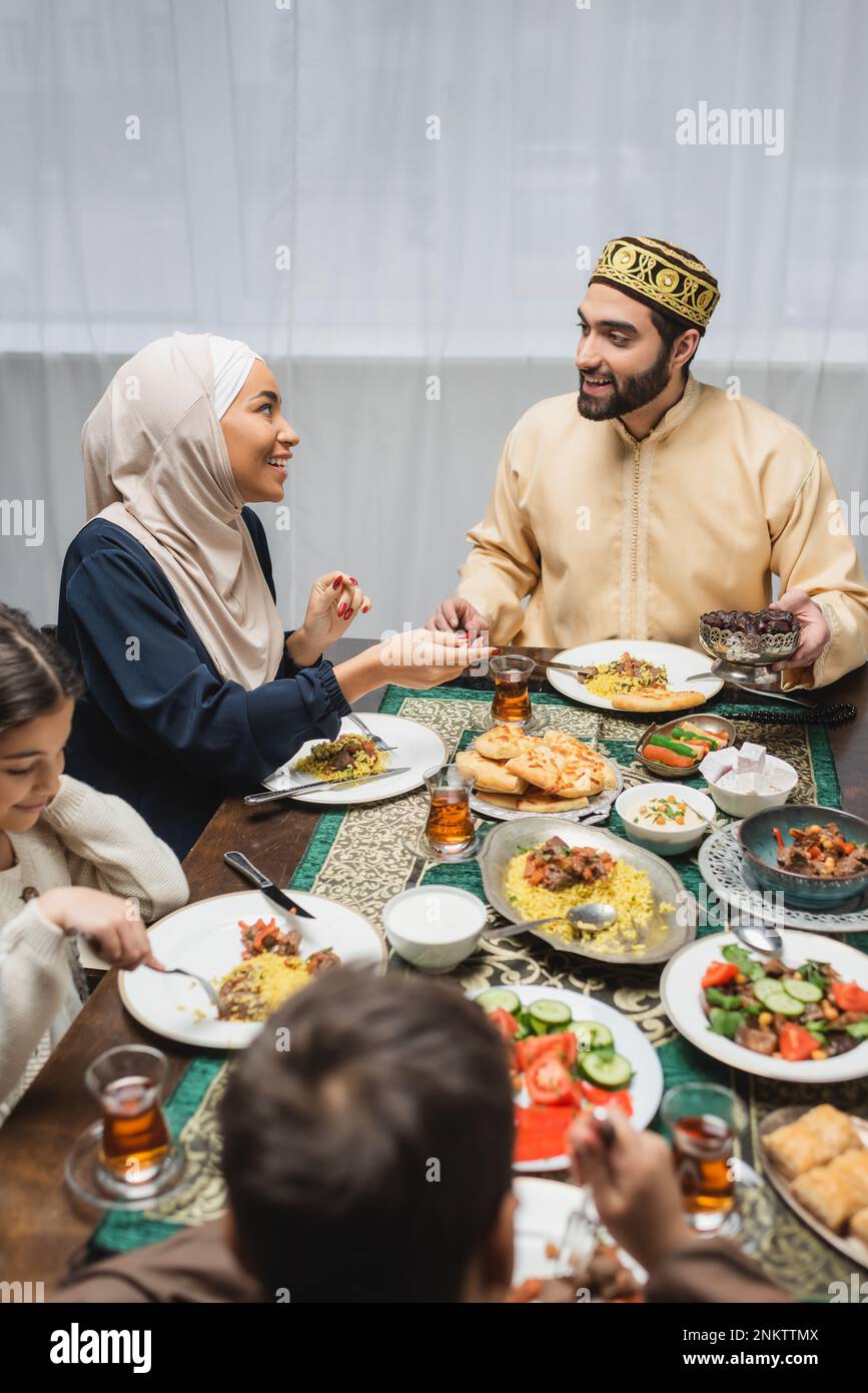 Smiling muslim parents talking near kids and iftar dinner at home,stock image Stock Photo