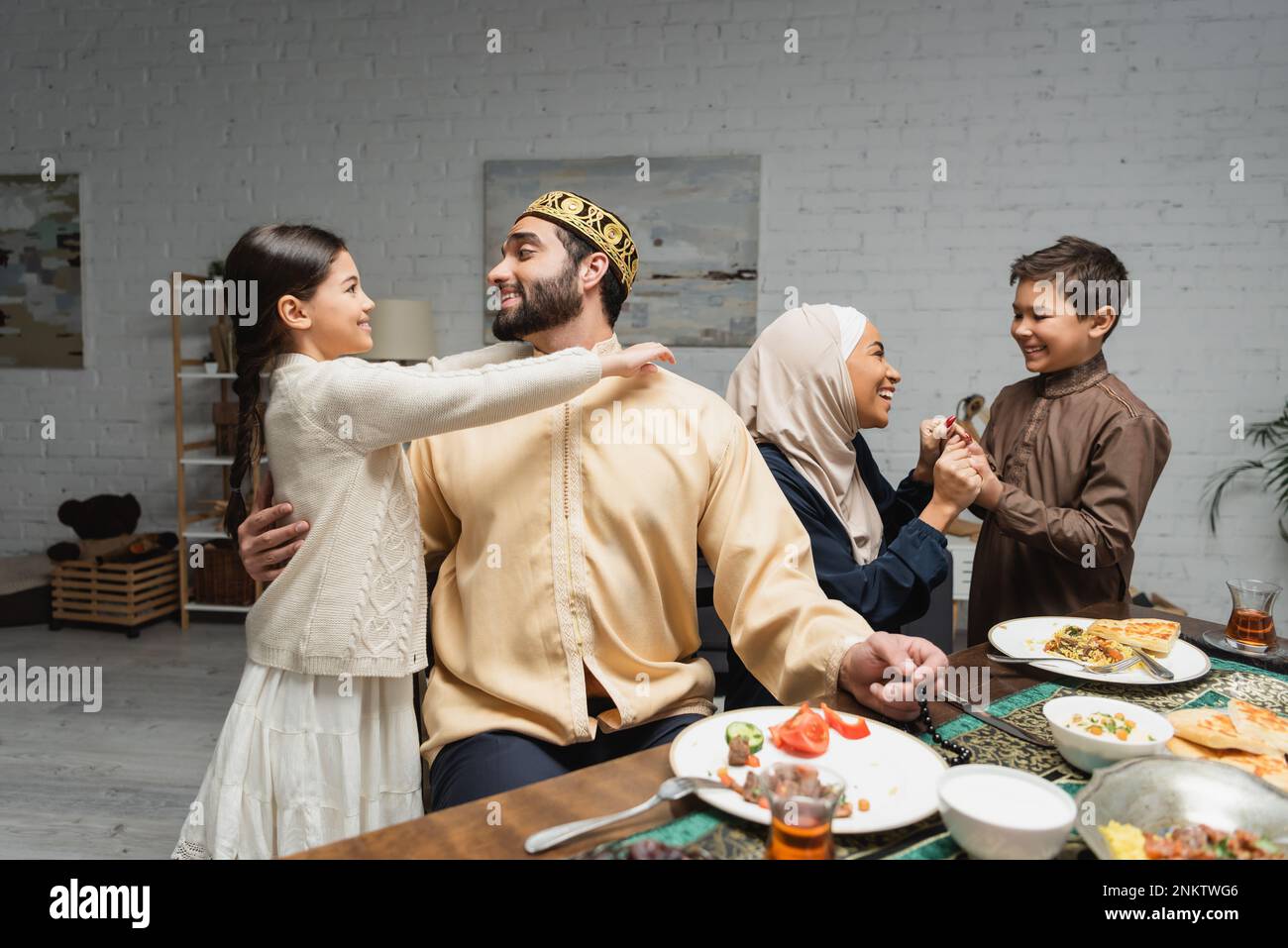 Cheerful middle eastern family hugging and talking during ramadan dinner at home,stock image Stock Photo
