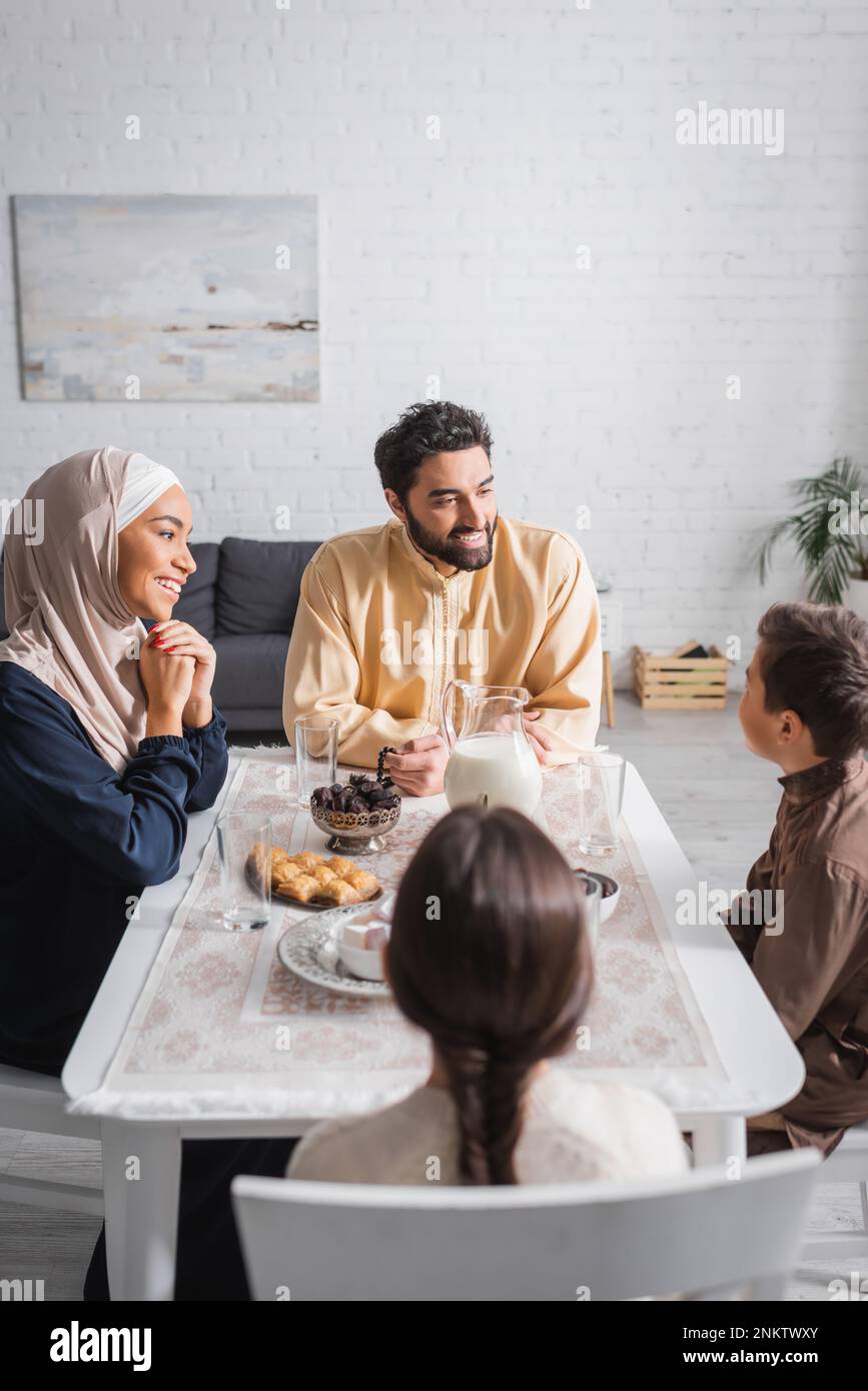 Smiling muslim family talking near food during ramadan at home,stock image Stock Photo