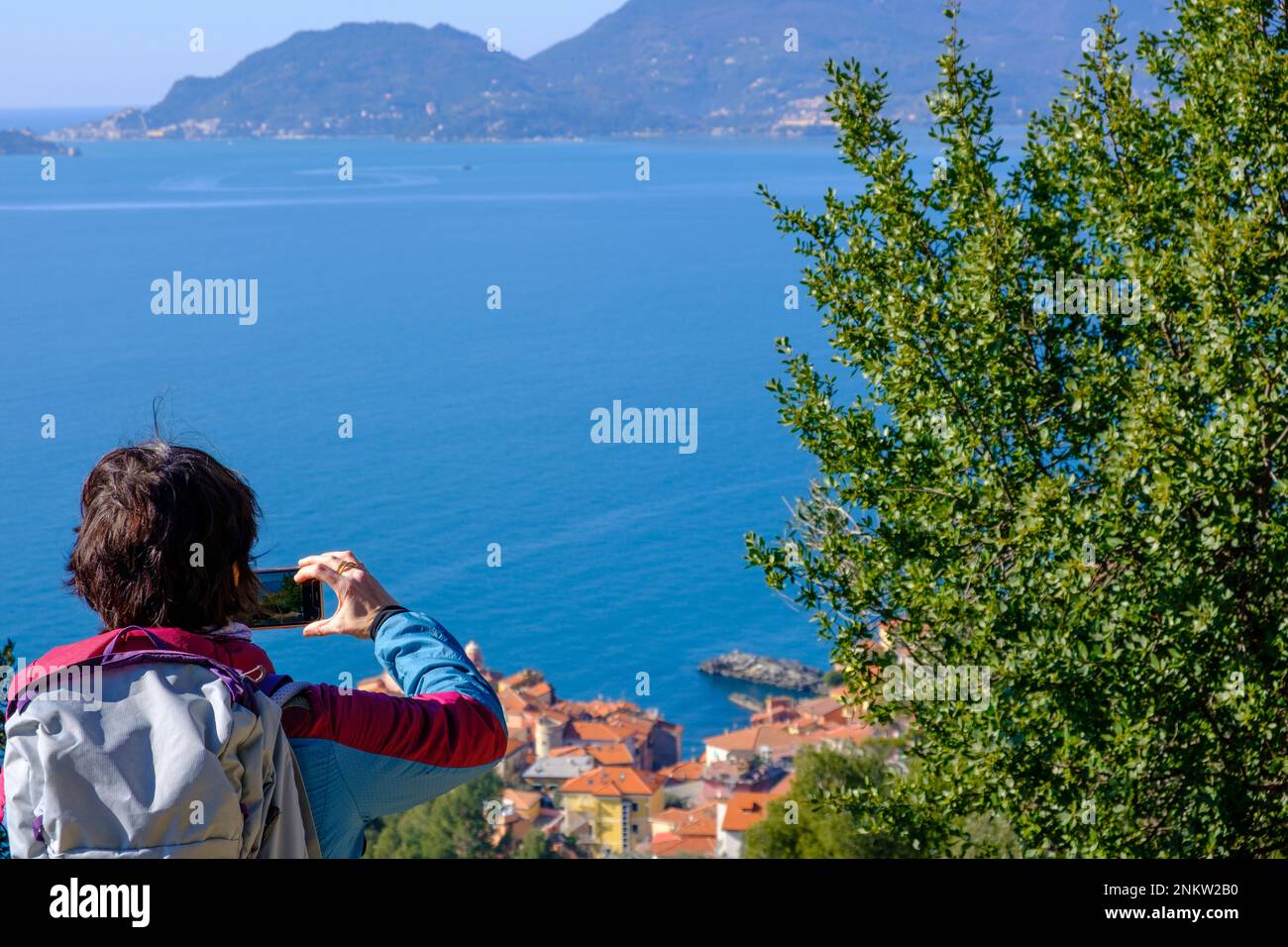 Woman taking picture of Tellaro and the Poet Gulf, Liguria region, Italy Stock Photo