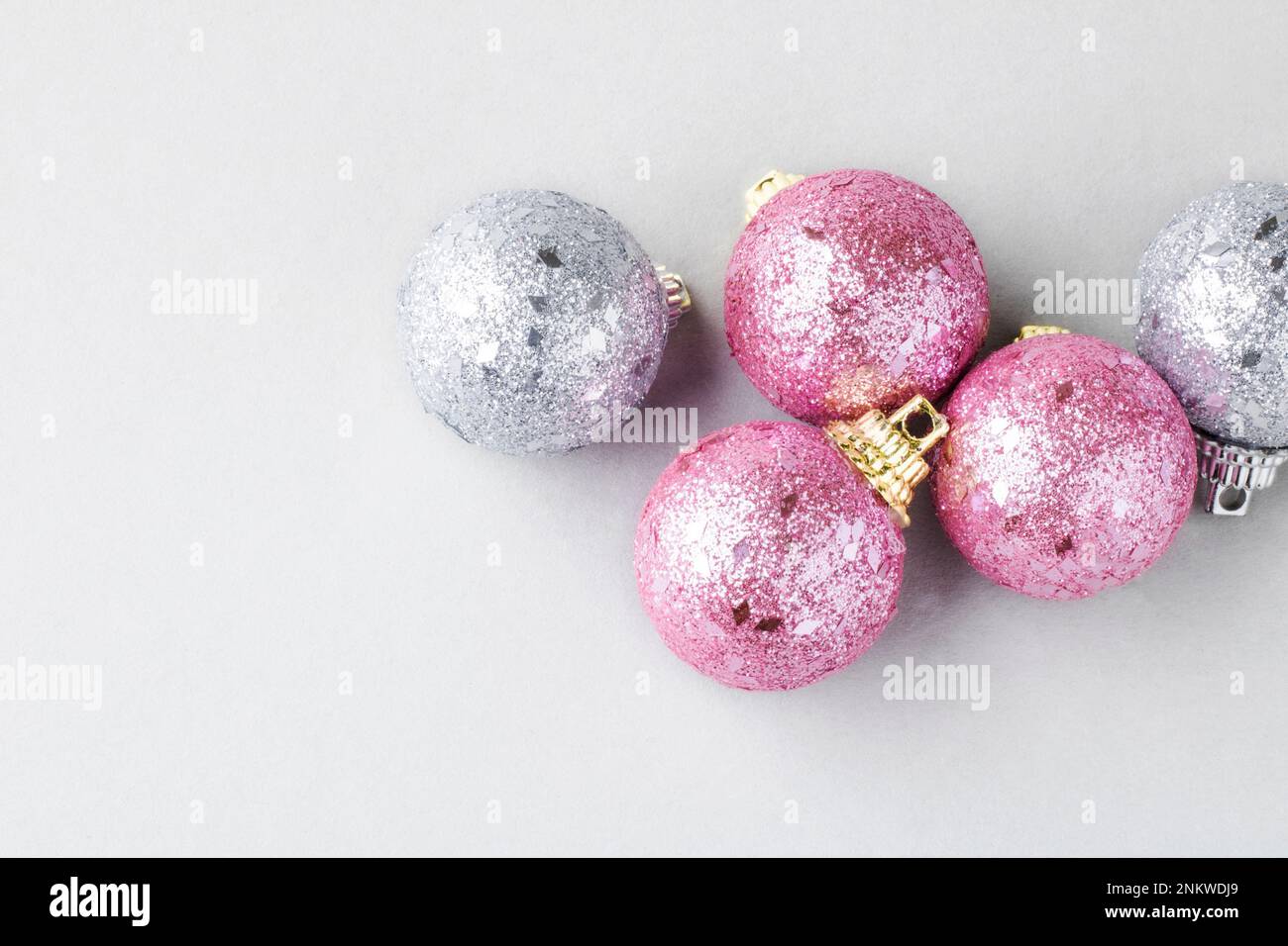 Pink and silver christmas balls isolated on gray background. Christmas and New Year background greeting card concept. Selective focus. Close up. Top v Stock Photo