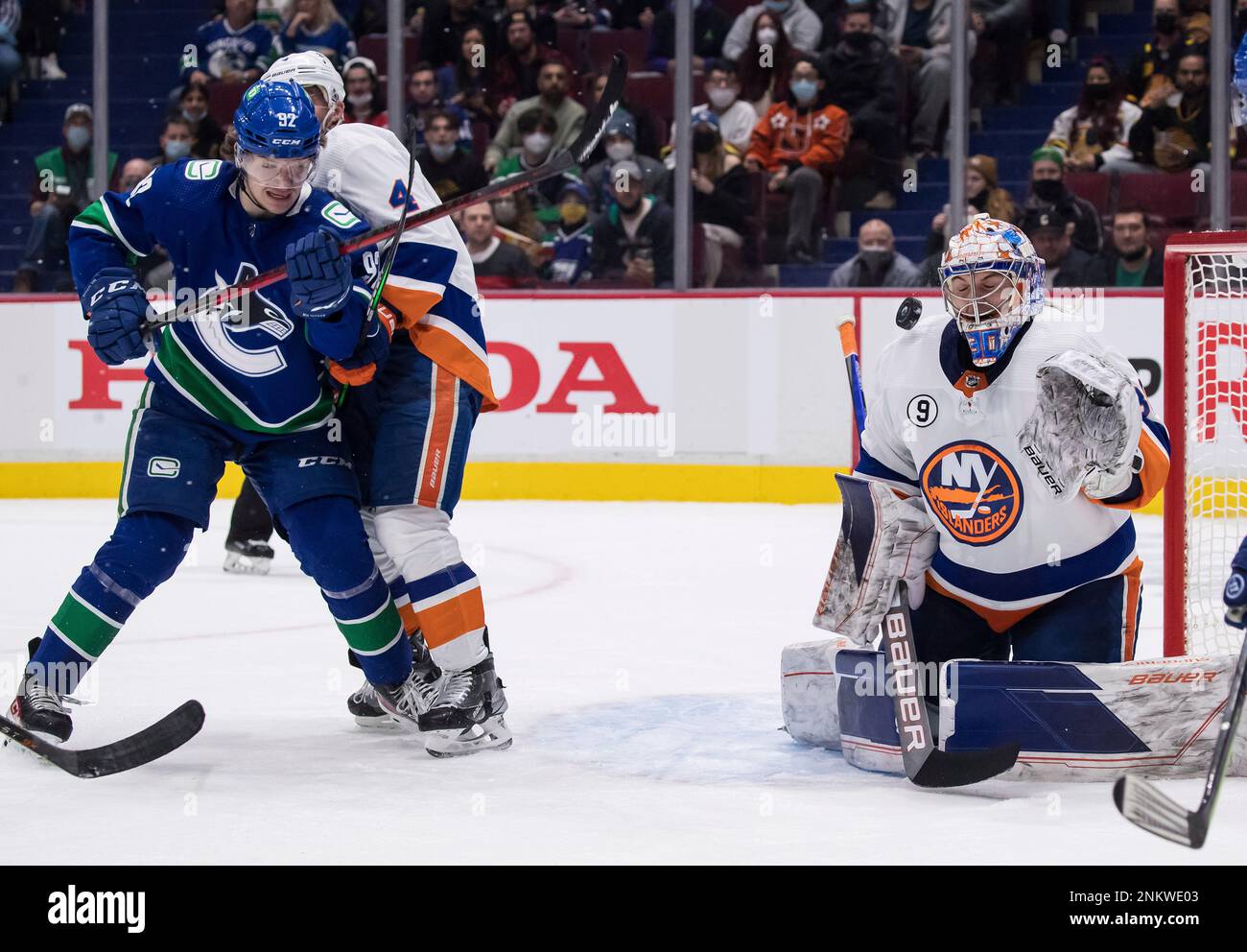 A shot deflects off the mask of Vancouver Canucks goalie Jacob Markstrom,  right, of Sweden, as Calgary Flames' Troy Brouwer tries to get his stick on  the puck during the second period of an NHL hockey game in Vancouver,  British Columbia, Saturday, Oct