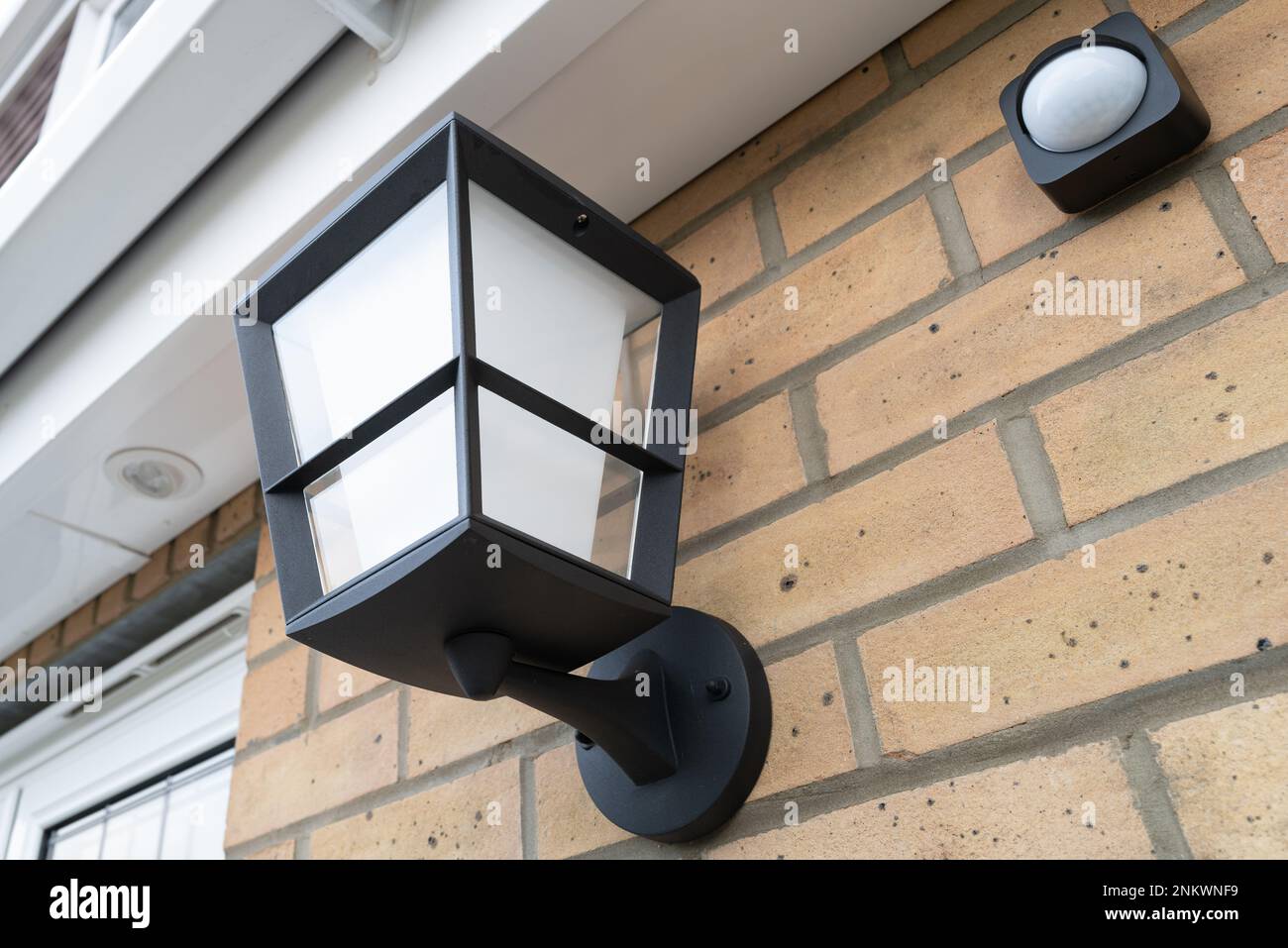 Newly installed multi-colour outdoor smart light seen together with a wireless PIR detector. Stock Photo