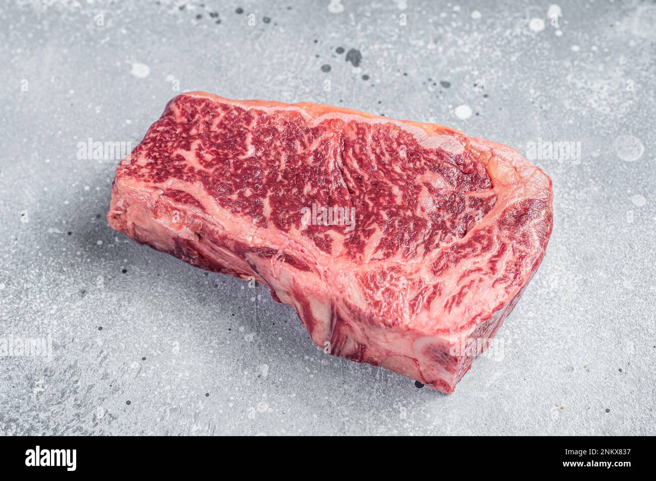 Raw Wagyu striploin or New york steak on a butcher table. Gray background. Top view. Stock Photo