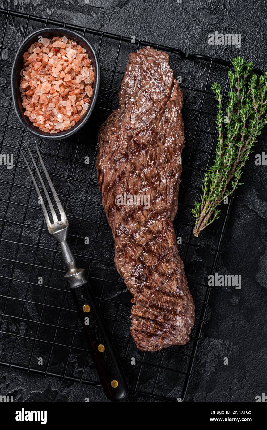 Grilled meat steak Machete skirt on a rack. Black background. Top view. Stock Photo