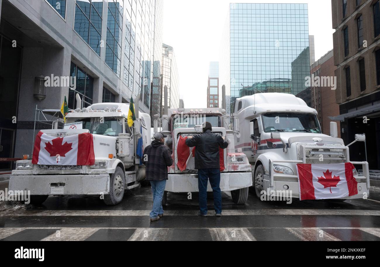 FILE - Truck drivers hang a Canadian flag on the front grill of a truck  parked in downtown Ottawa, Ontario, near Parliament Hill on Wednesday, Feb.  2, 2022. On Friday, Feb. 4,
