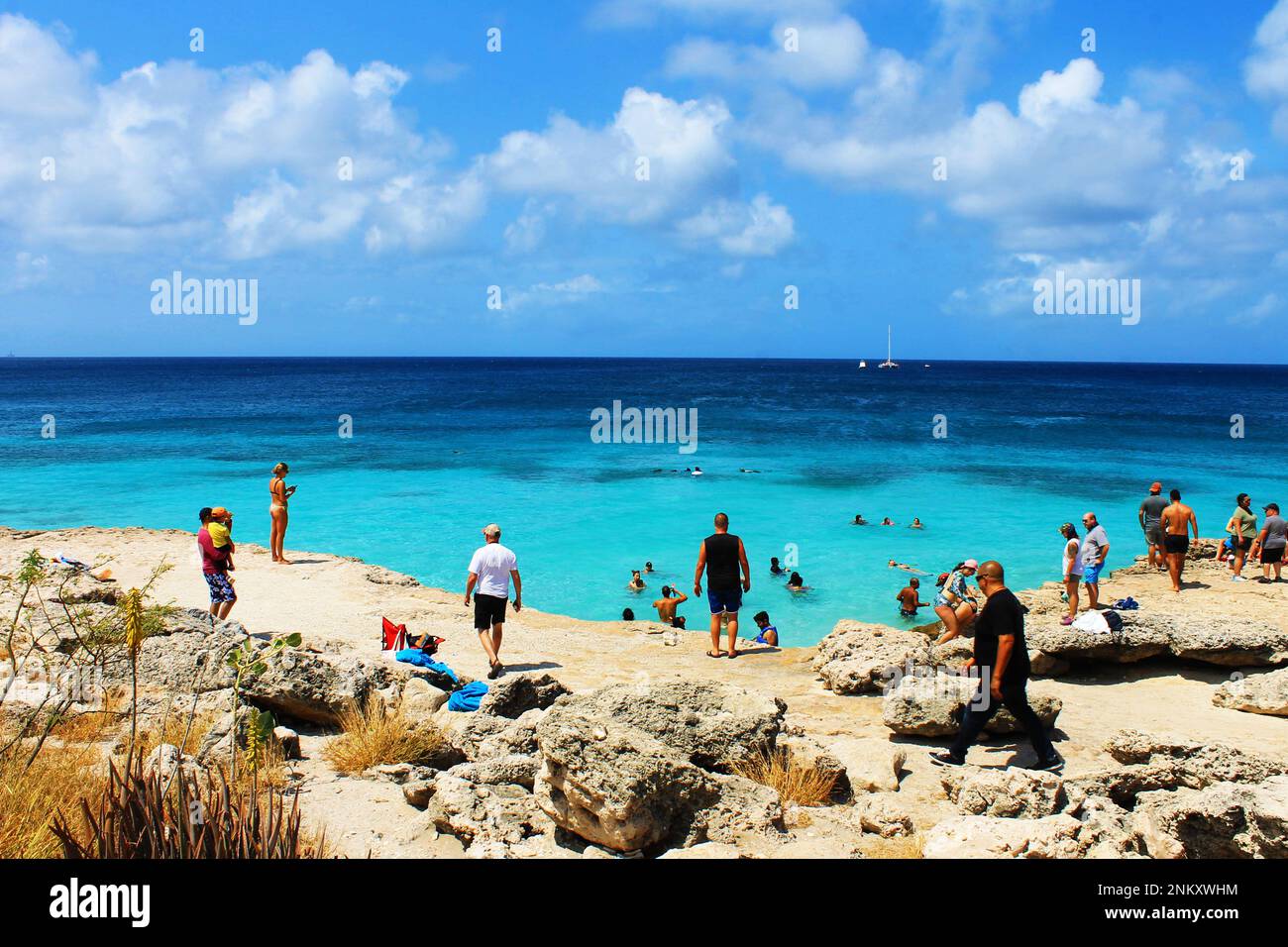 Tres Trapi Beach, Noord, Aruba - March 10, 2022. People on the beach and in the water, Beach is surrounded by a volcanic rock formation. Stock Photo