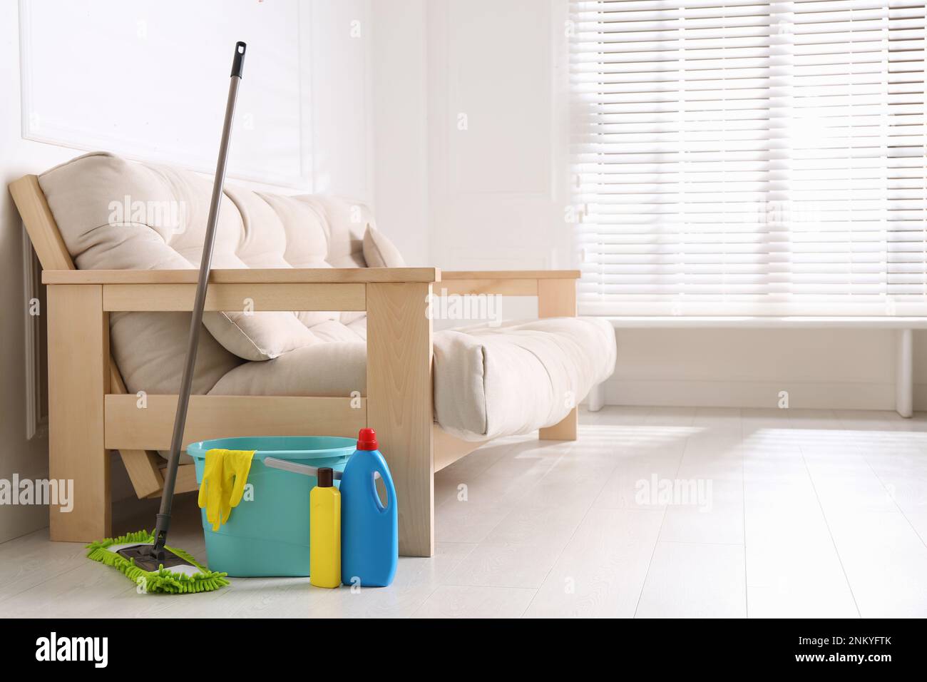 Floor mop, cleaning detergents and bucket with gloves in living room