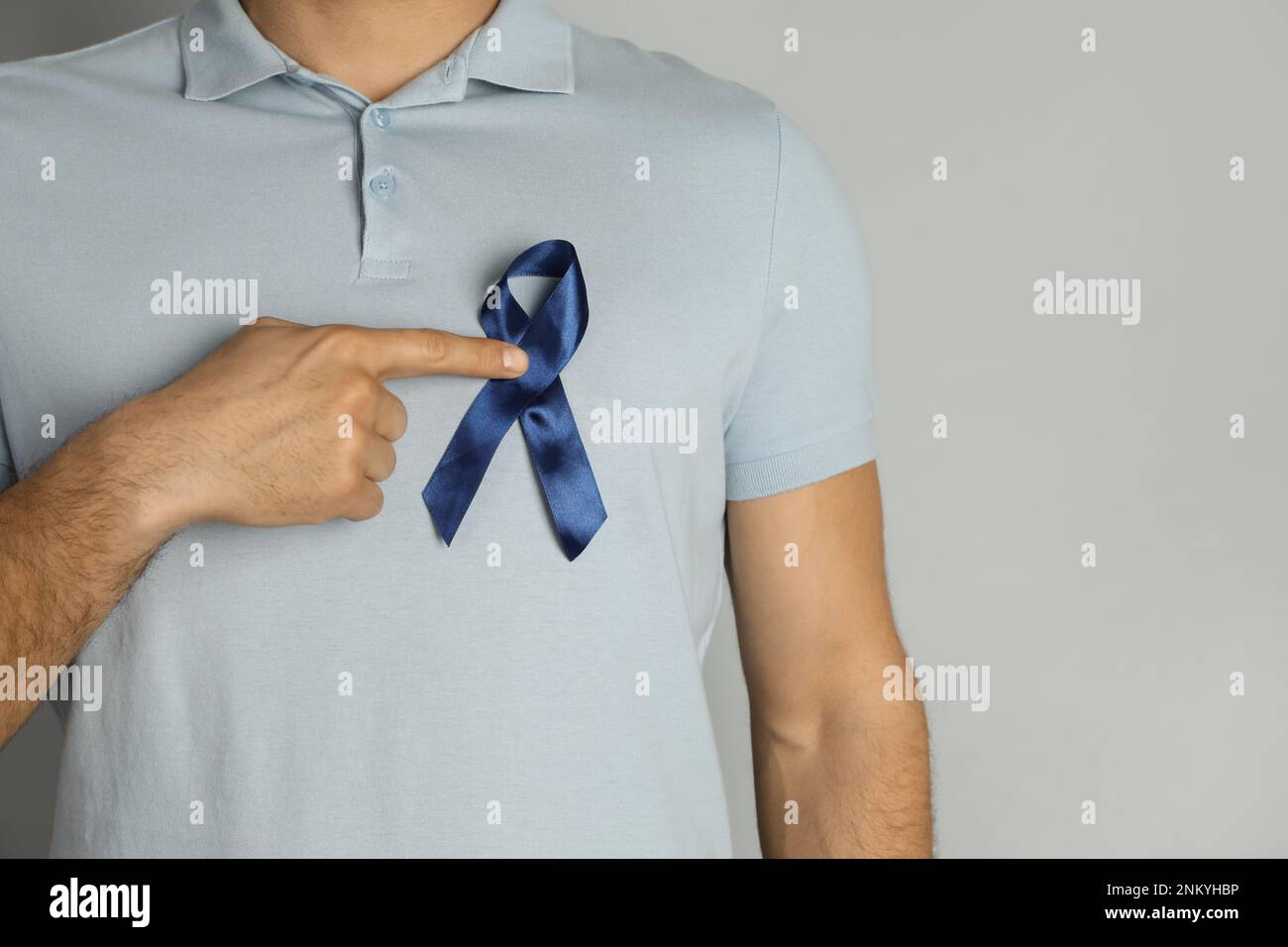 Man With Ribbon Man with blue ribbon on grey background, closeup. Urology cancer ...
