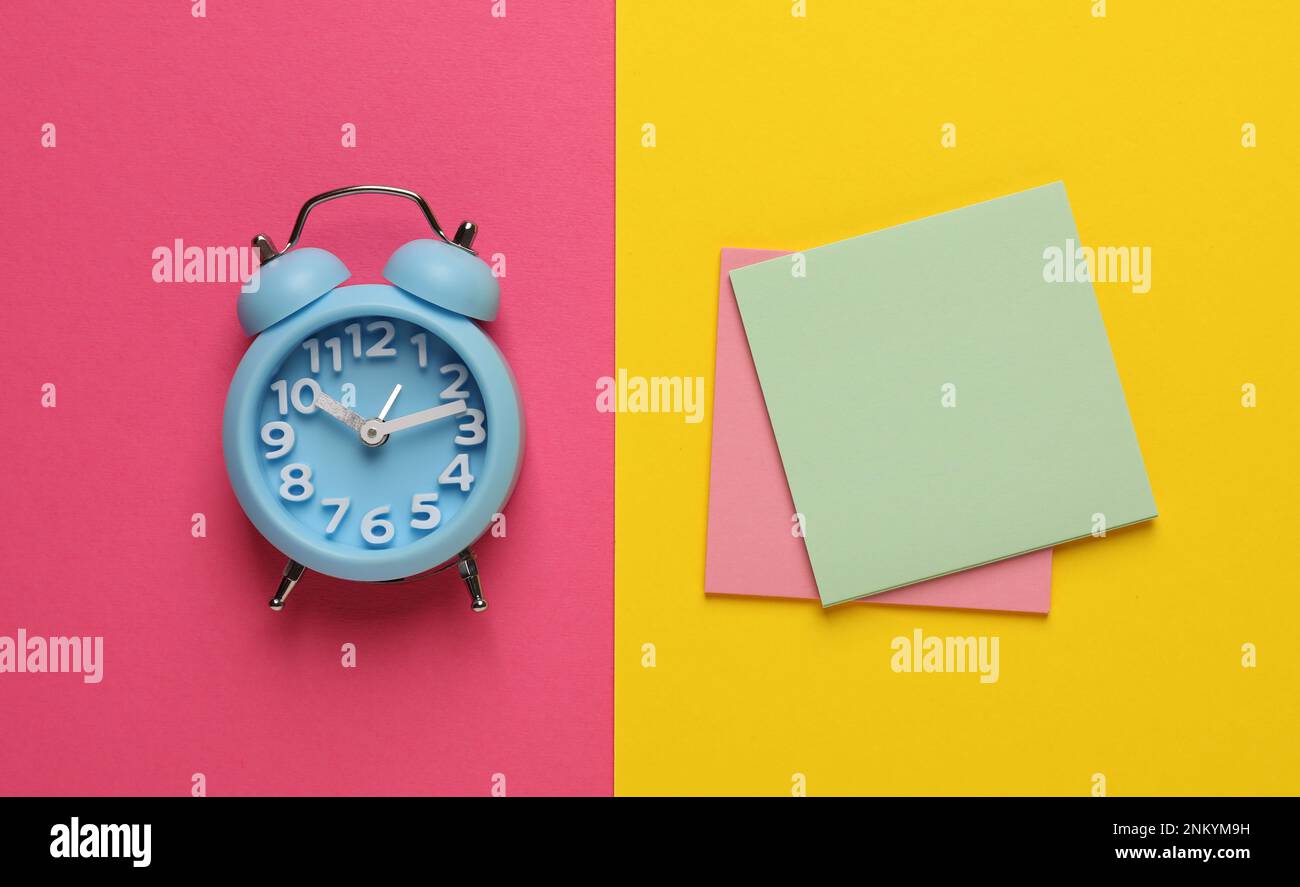Alarm clock and blank reminder notes on color background, flat lay Stock Photo