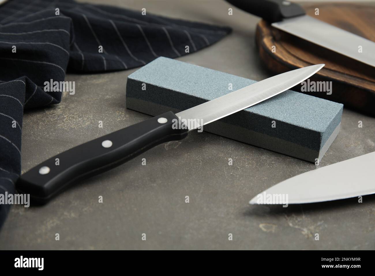 https://c8.alamy.com/comp/2NKYM9R/sharpening-stone-and-knives-on-grey-table-closeup-2NKYM9R.jpg