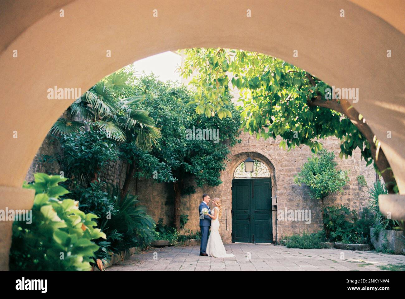 View from the arch to the hugging bride and groom in the courtyard of ...