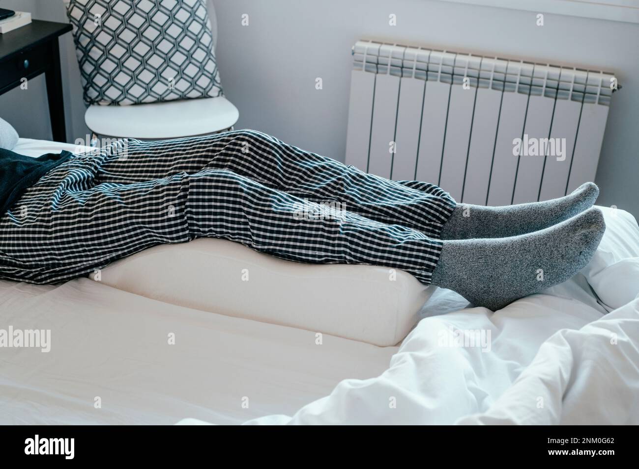 closeup of a man in bed leaning his legs on a leg elevation pillow made