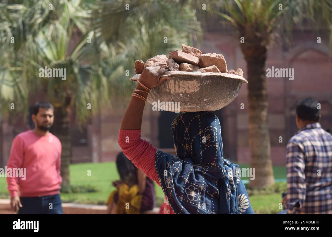 A female labourer carrying a basket of bricks on her head Stock Photo