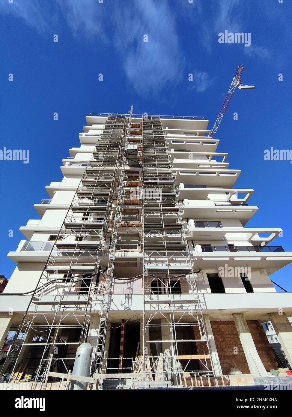Curated visual reference: Durable And High Quality Apartment Building Construction Reference: An Apartment Building Construction Site With Scaffolding And A Crane