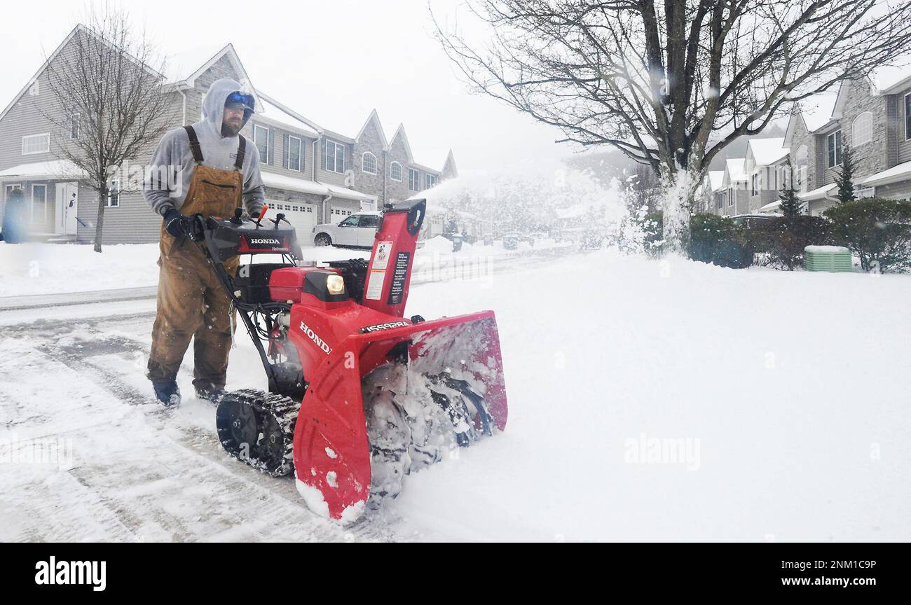 Joe Miscavage uses a snow blower to clear a driveway at Marina Pointe
