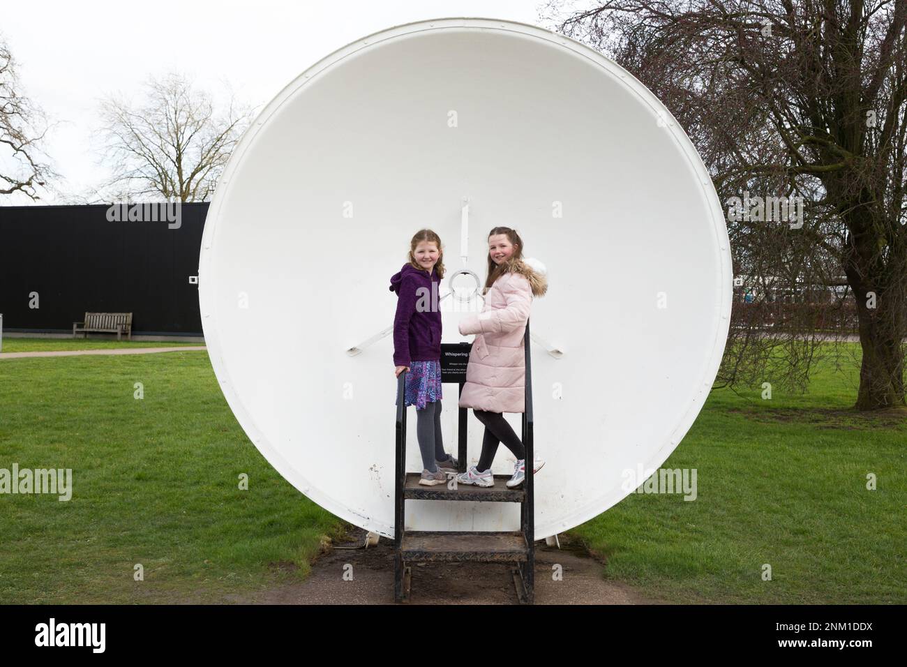 Kids / girls / children / child listen and speak at the Whispering Dish / Dishes which act as an acoustic mirror to transmit and focus sound waves. (133) Stock Photo