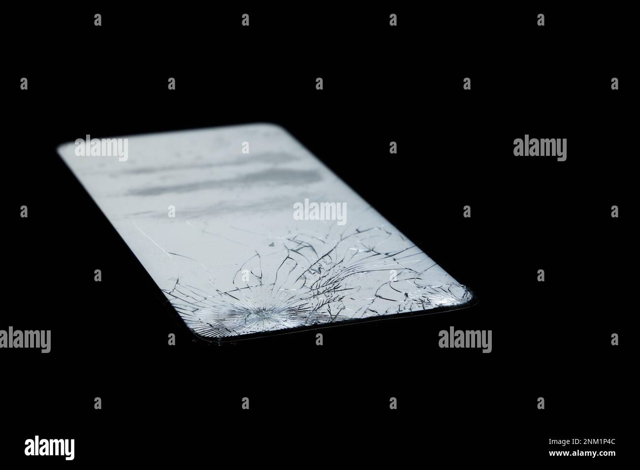 Mobile phone with broken glass and white screen in the darkness Stock Photo
