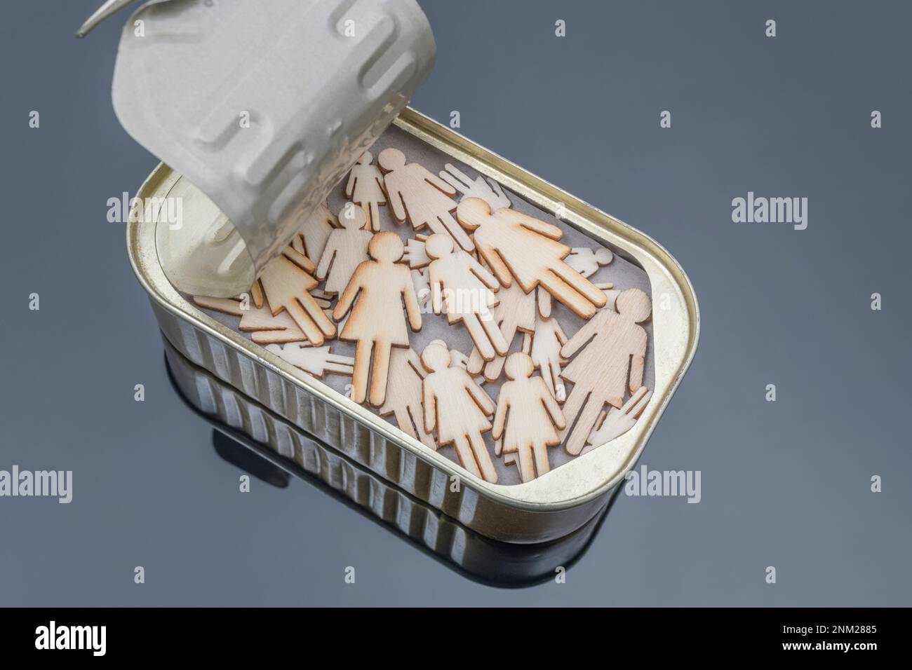 Female laser-cut wooden figures squashed into a sardine tin. Possibly for female gender politics, LGBT etc. concept. Stock Photo