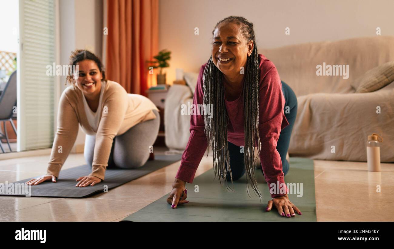 Happy mother with daughter doing exercises at home Stock Photo
