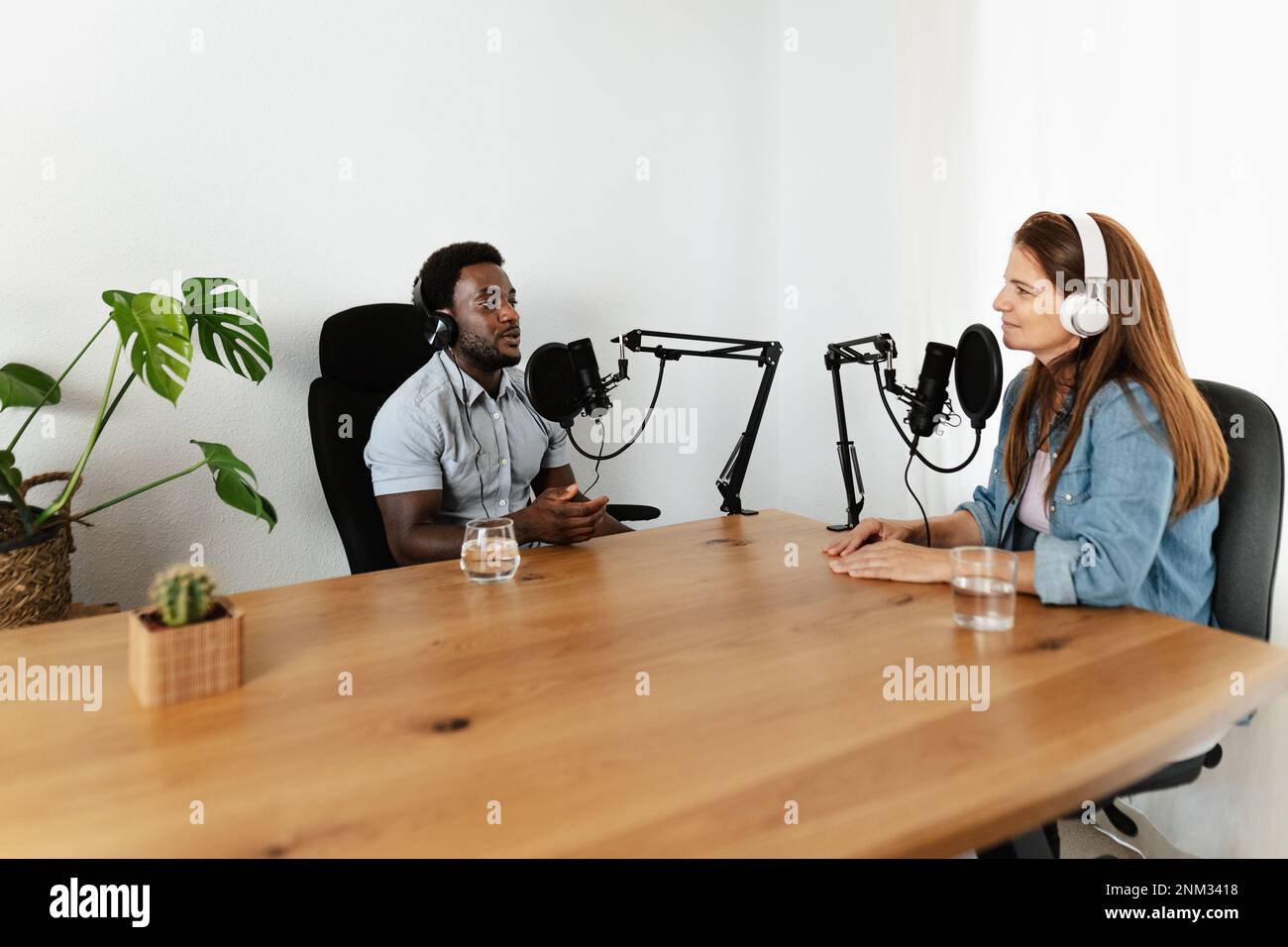 Multiracial people recording a podcast using microphone and headphones from home studio Stock Photo