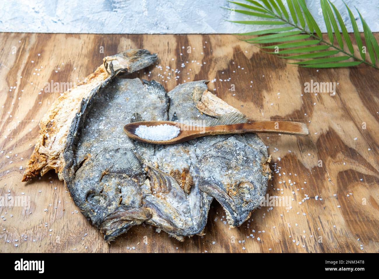 Salted cod with a spoon of sea salt and a palm leaf Stock Photo