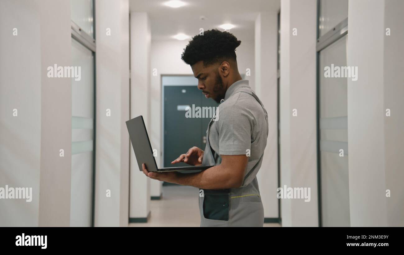 African American installer in uniform stands in hallway and sets up