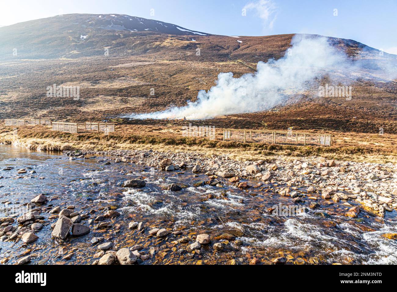 The controlled burning of heather moorland (swailing or muirburn) beside Clunie Water on the slopes of Sgor Mor south of Braemar, Aberdeenshire, Scotl Stock Photo
