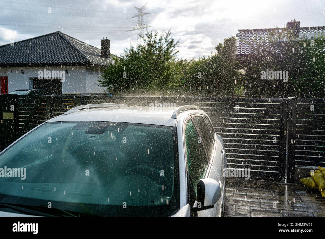 A silver passenger car parked in the driveway in front of the garage in