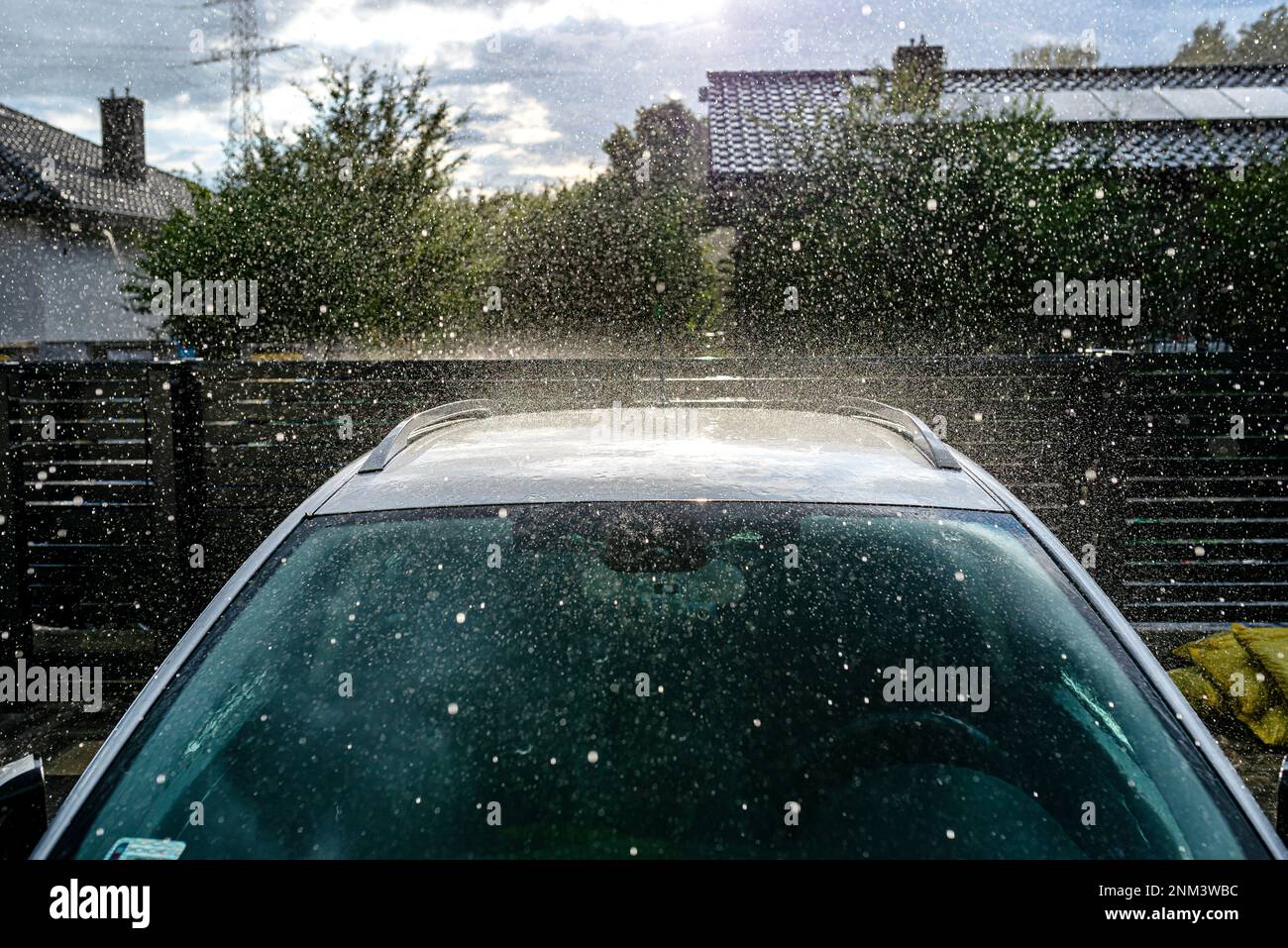 A silver passenger car parked in the driveway in front of the garage in