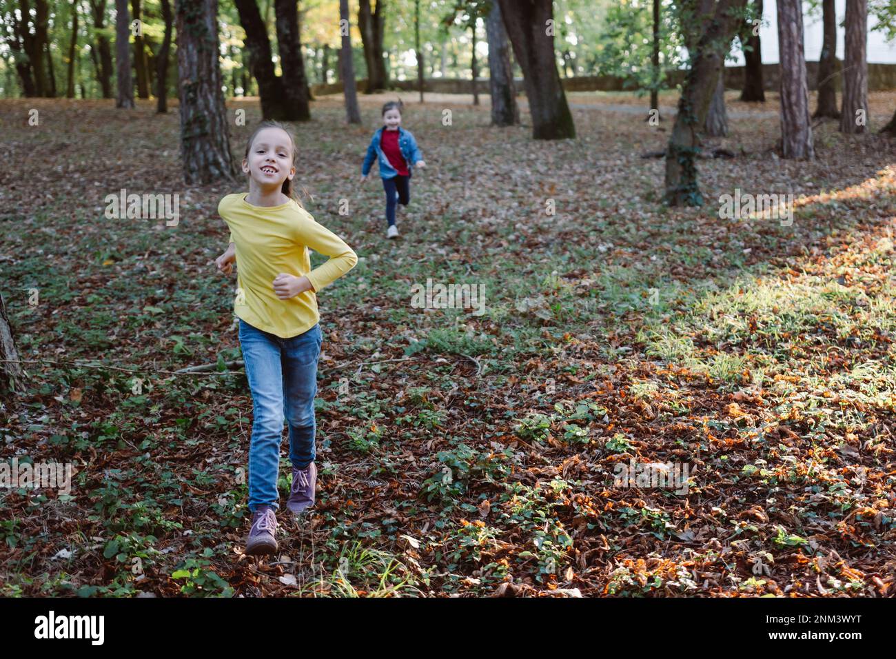 Full length of two happy girls running in autumn park Stock Photo