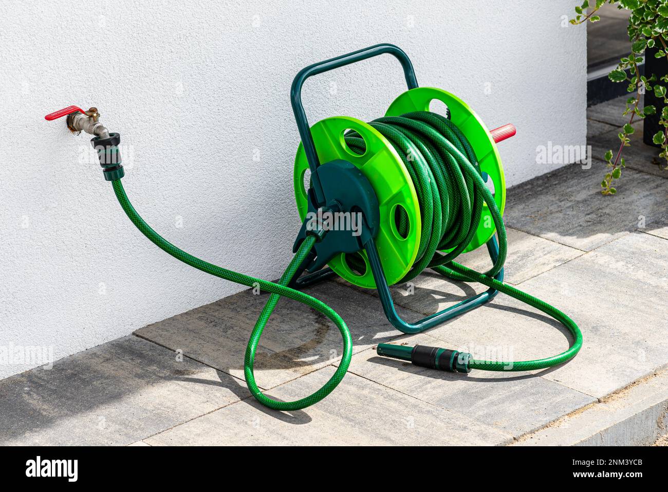 A garden hose connected to a faucet protruding from a building against