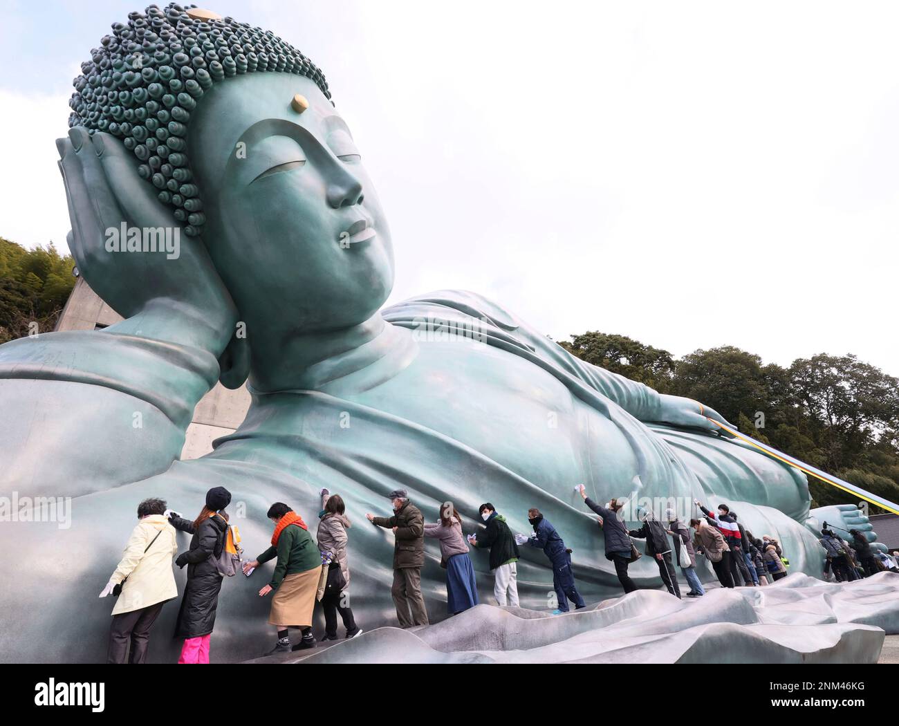 Approximately 200 Buddhist priests and believers clean a reclining